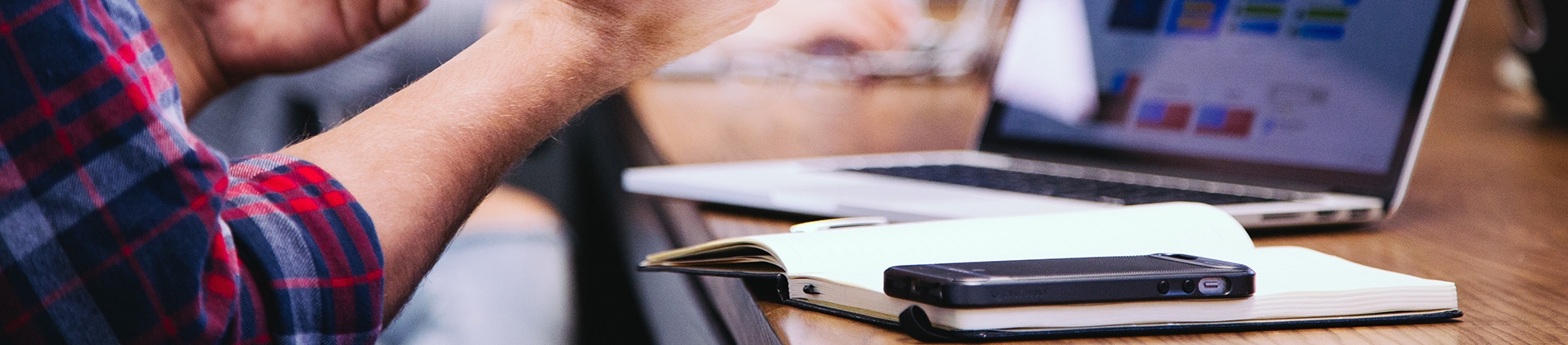 A man sat talking at a desk with a laptop and open notebook A man sat talking at a desk with a laptop and open notebook