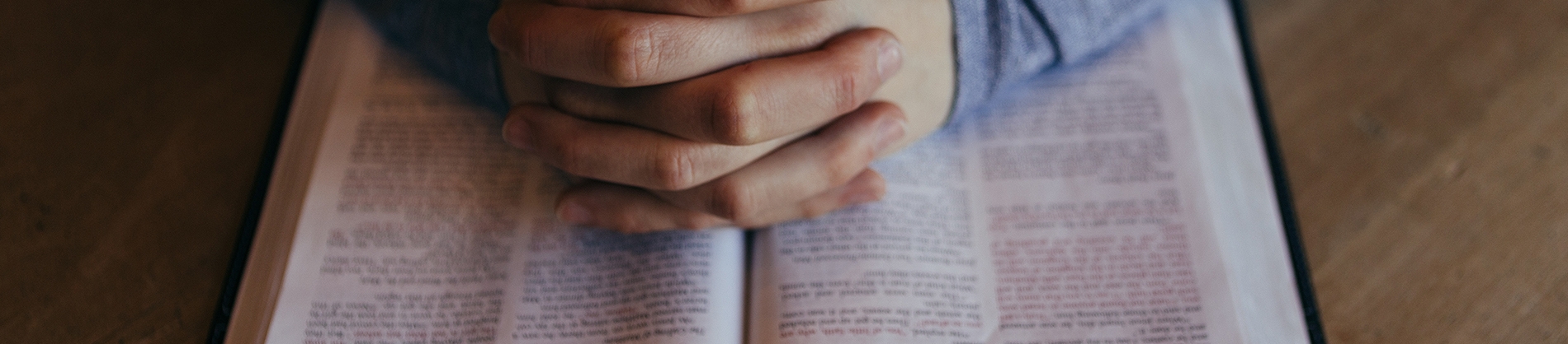 Praying hands on top of a open bible Praying hands on top of a open bible