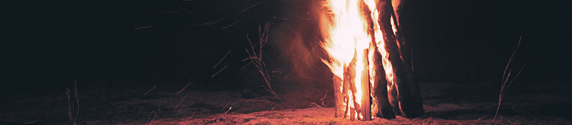 A pile of wood on fire on a beach