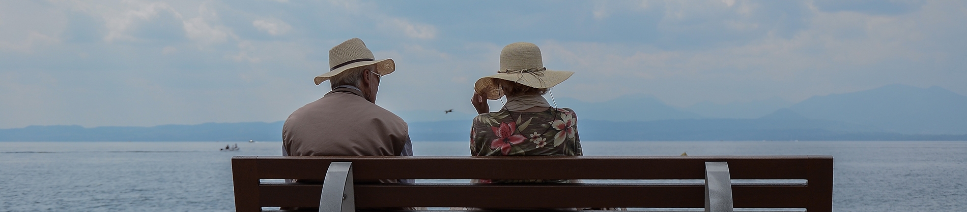 A elderly couple sat on a bench looking out to sea A elderly couple sat on a bench looking out to sea