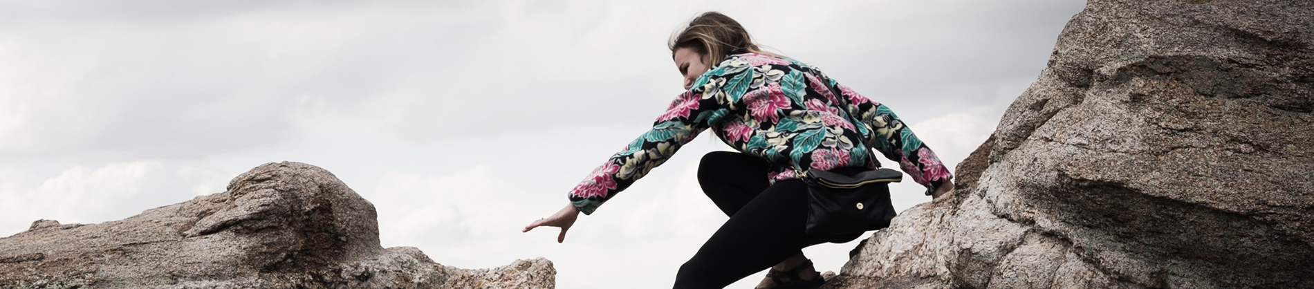 A women climbing rocks. She is reaching for another rock A women climbing rocks. She is reaching for another rock