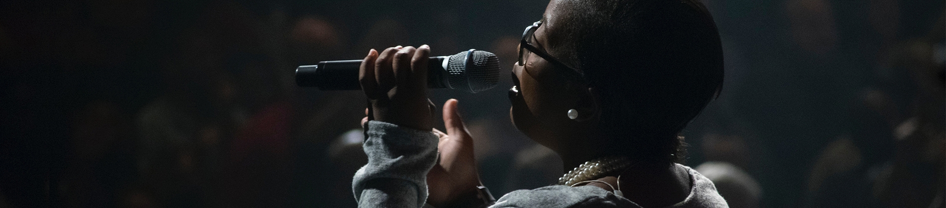 A women with a microphone singing to a audience A women with a microphone singing to a audience