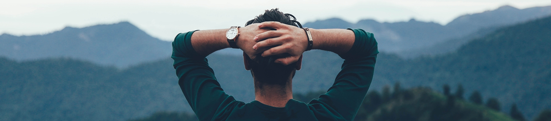 A man sitting look over a mountain landscape with his hands behind his head A man sitting look over a mountain landscape with his hands behind his head