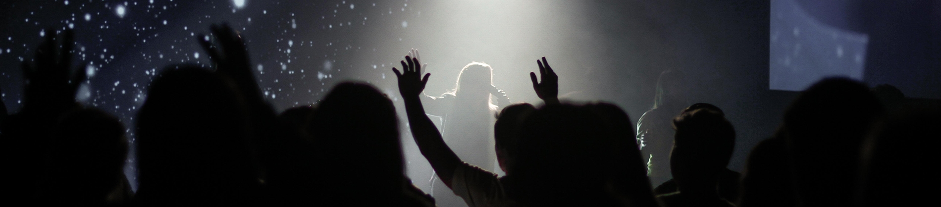 A women leading worship, congregation with their hands in the air A women leading worship, congregation with their hands in the air
