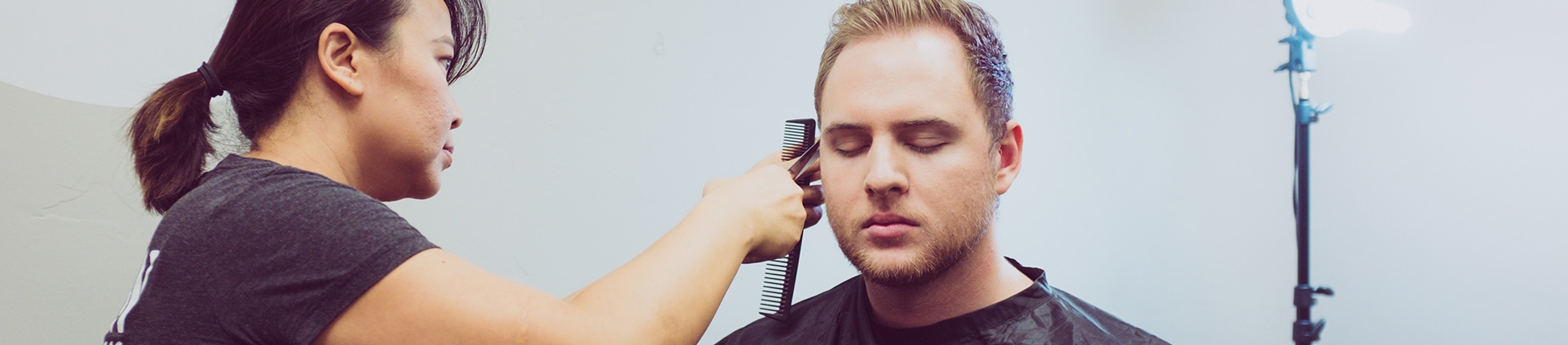 A women cutting a man's hair in a barbers shop A women cutting a man's hair in a barbers shop