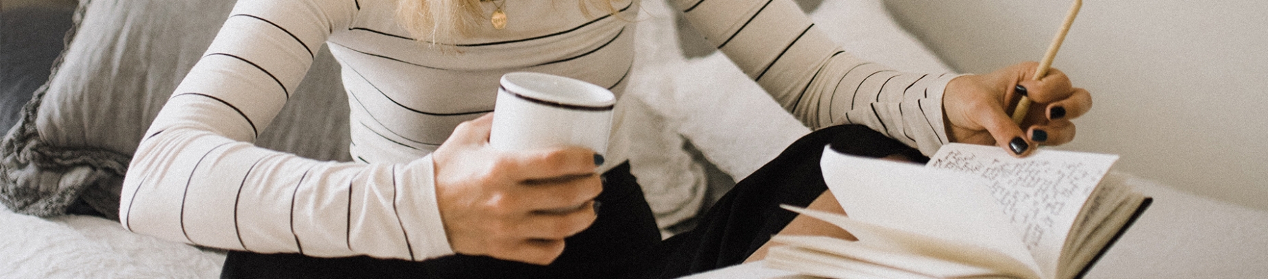 A women sat on her bed with a mug and notebook A women sat on her bed with a mug and notebook