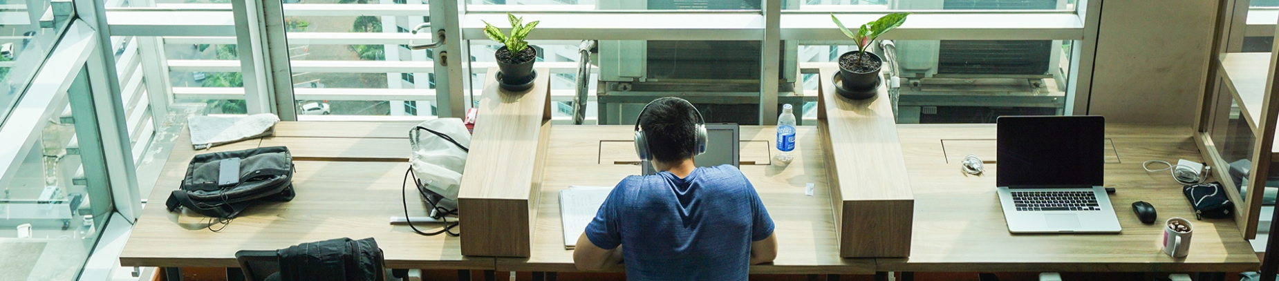 A man sat at a desk with headphones on A man sat at a desk with headphones on