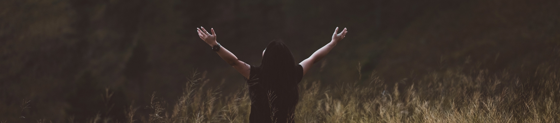 A women in a field with her hands up in the air A women in a field with her hands up in the air