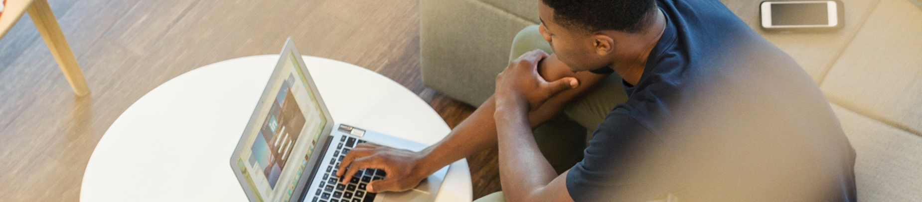 A guy working on his laptop on a coffee table A guy working on his laptop on a coffee table
