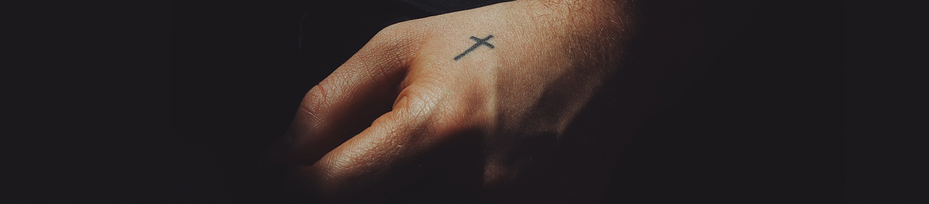 A mans hand with the a small cross drawn on it A mans hand with the a small cross drawn on it