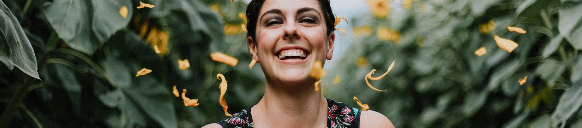 A women laughing with orange petals falling around her A women laughing with orange petals falling around her