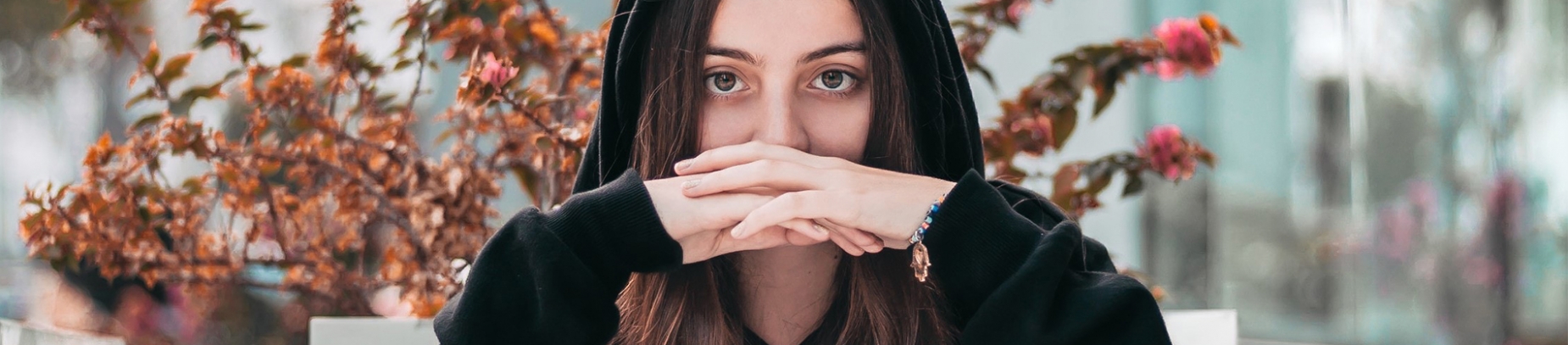 A woman with her hoodie hood up with her hands crossed in front of her A woman with her hoodie hood up with her hands crossed in front of her