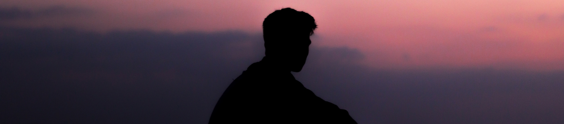 A silhouette of a man looking towards a sunset sky A silhouette of a man looking towards a sunset sky