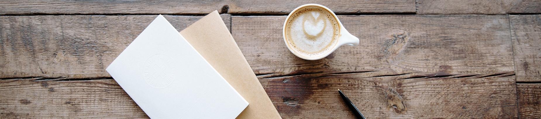 Wooden table with a blank card and envelope and a cup of coffee