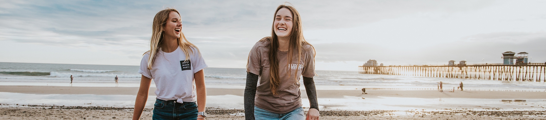 Two women walking and laughing on a beach together Two women walking and laughing on a beach together