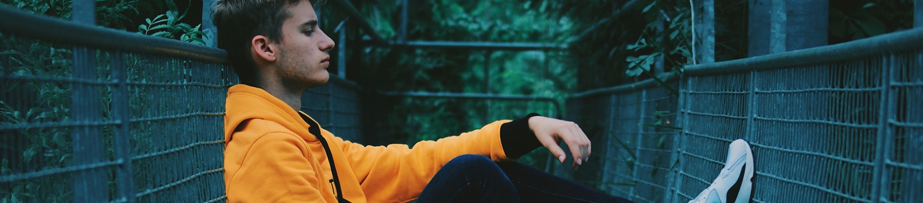 A man in an orange jacket sat up against railings A man in an orange jacket sat up against railings