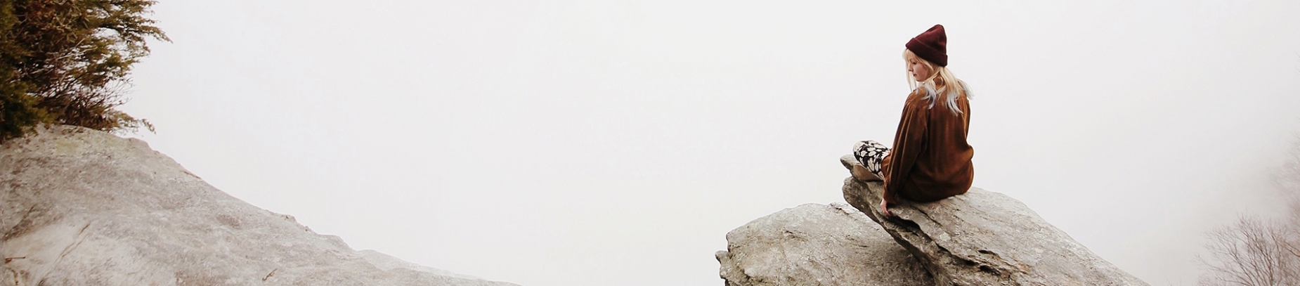 A women sat on the edge of a rock into the mist A women sat on the edge of a rock into the mist