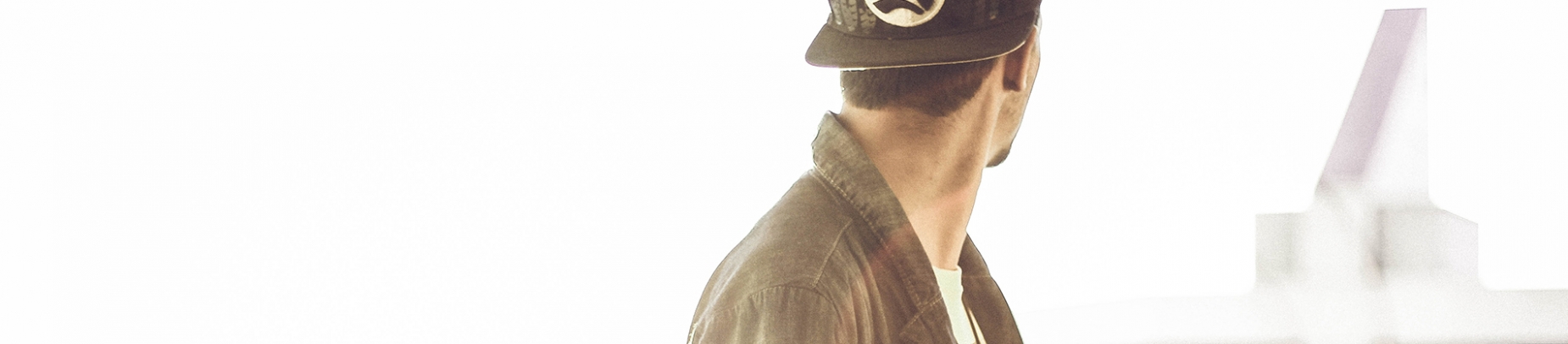 A man in a cap and jacket looking behind him into the distance A man in a cap and jacket looking behind him into the distance