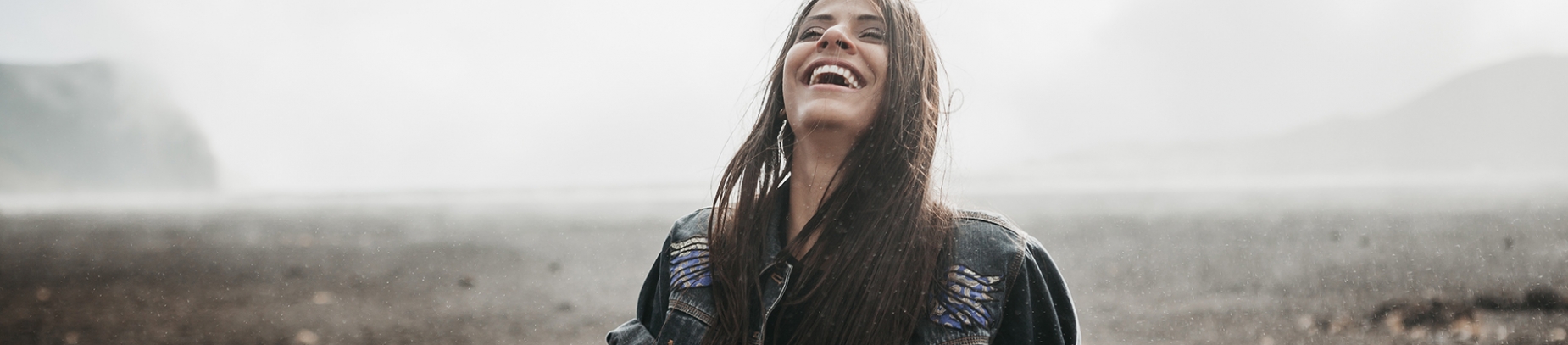 A women stood by the beach laughing A women stood by the beach laughing