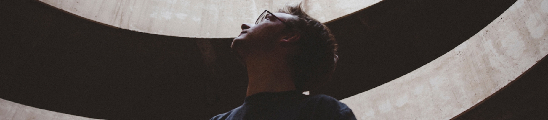 A man in a building looking up with the sun shining through the roof on him A man in a building looking up with the sun shining through the roof on him
