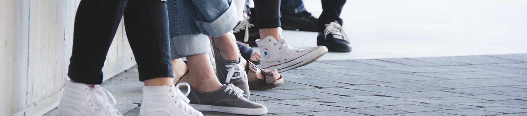 The feet of a group of people stood against a wall The feet of a group of people stood against a wall
