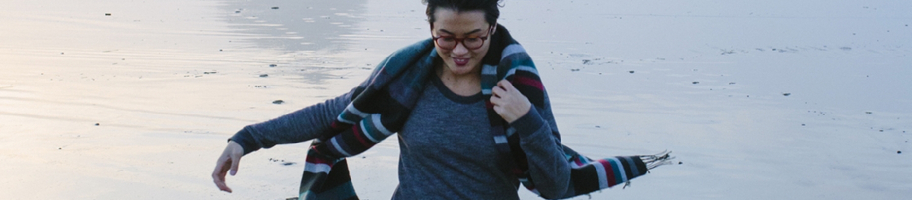 A women wearing a winter scarf running along a beach A women wearing a winter scarf running along a beach