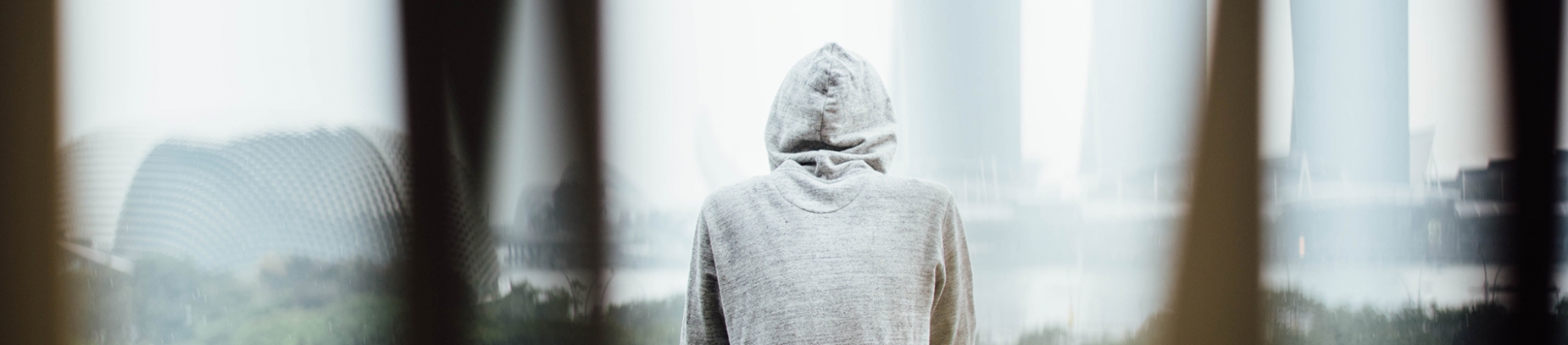A man with his hood up looking over balcony view A man with his hood up looking over balcony view