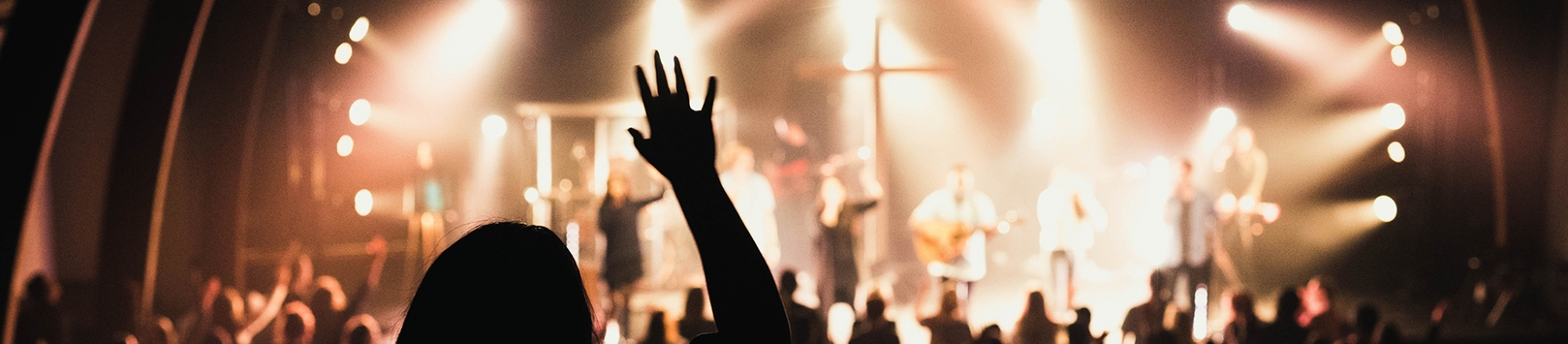 A church worship team on stage and a women with her hand in the air A church worship team on stage and a women with her hand in the air