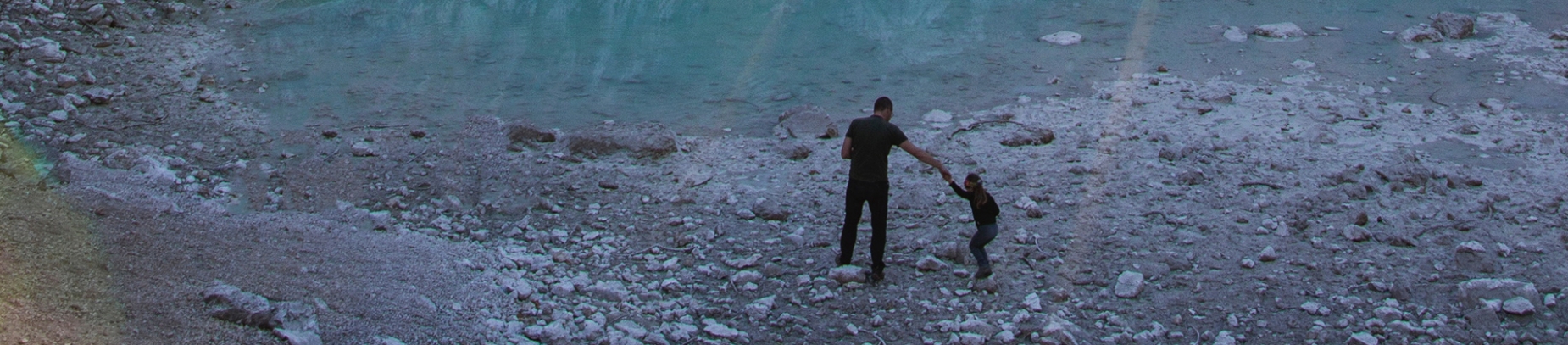 A father and son walking on some rocks beside a lake A father and son walking on some rocks beside a lake
