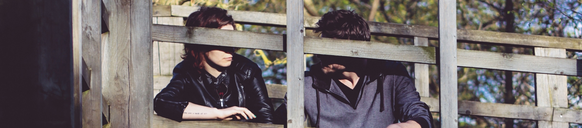 A man and woman sat on a wooden bridge together A man and woman sat on a wooden bridge together