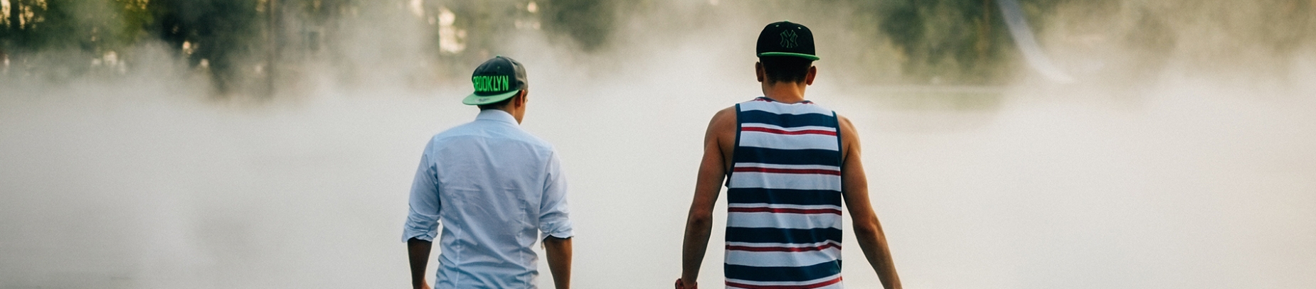 Two men in baseball hats walking into a cloud of smoke Two men in baseball hats walking into a cloud of smoke
