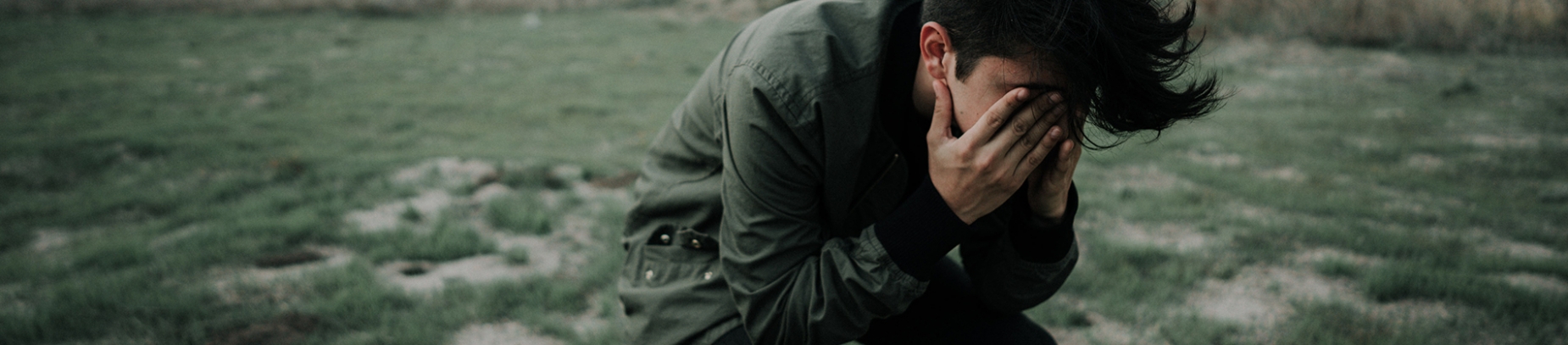 A guy sitting down with his hands over his face A guy sitting down with his hands over his face