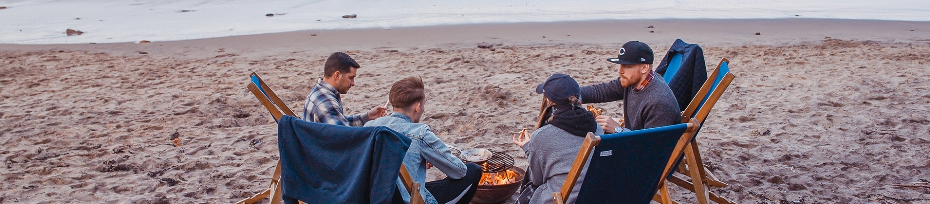A group of friends sat around a fire on the beach A group of friends sat around a fire on the beach
