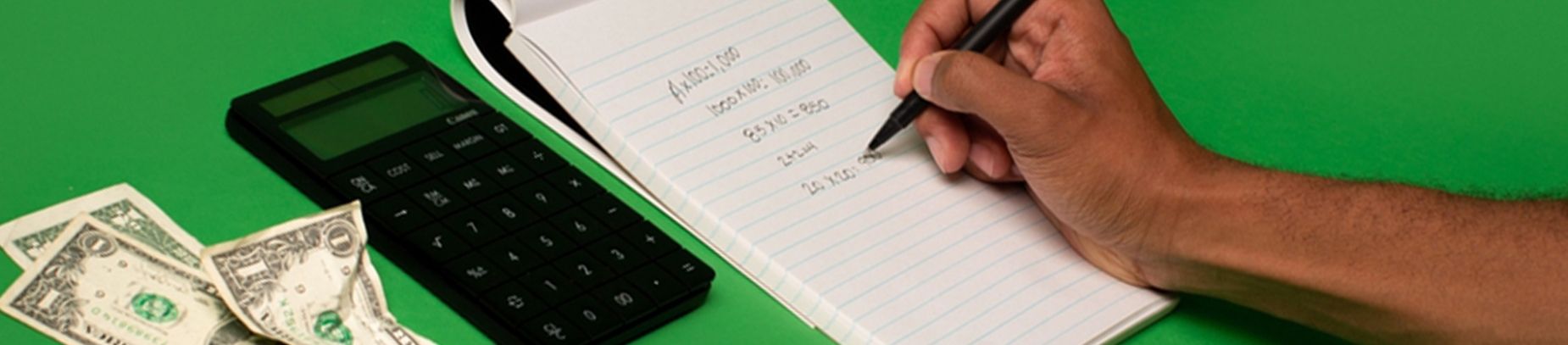 A man writing down numbers on a notepad with a calculator A man writing down numbers on a notepad with a calculator