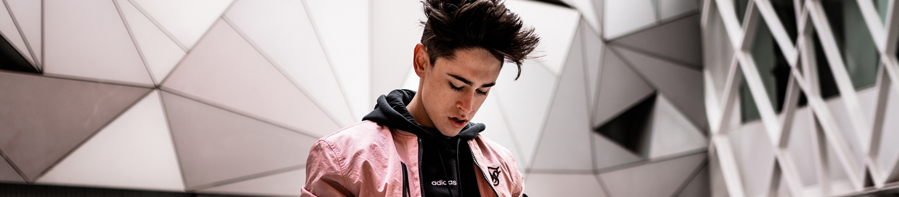 A guy with geometric walls behind him looking down at the floor A guy with geometric walls behind him looking down at the floor