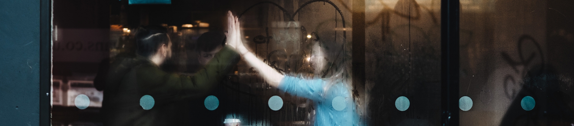 A man and a women sat inside a coffee shop high fiving