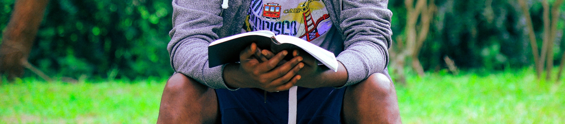 A man sat in a park reading his bible A man sat in a park reading his bible