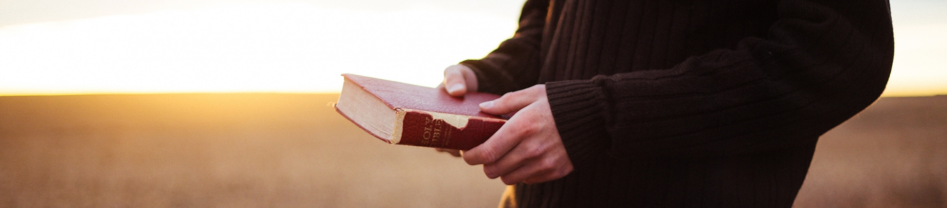 A guy in a jumper holding a brown bible A guy in a jumper holding a brown bible