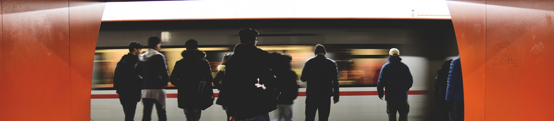 A group of people waiting on a platform with a train coming past