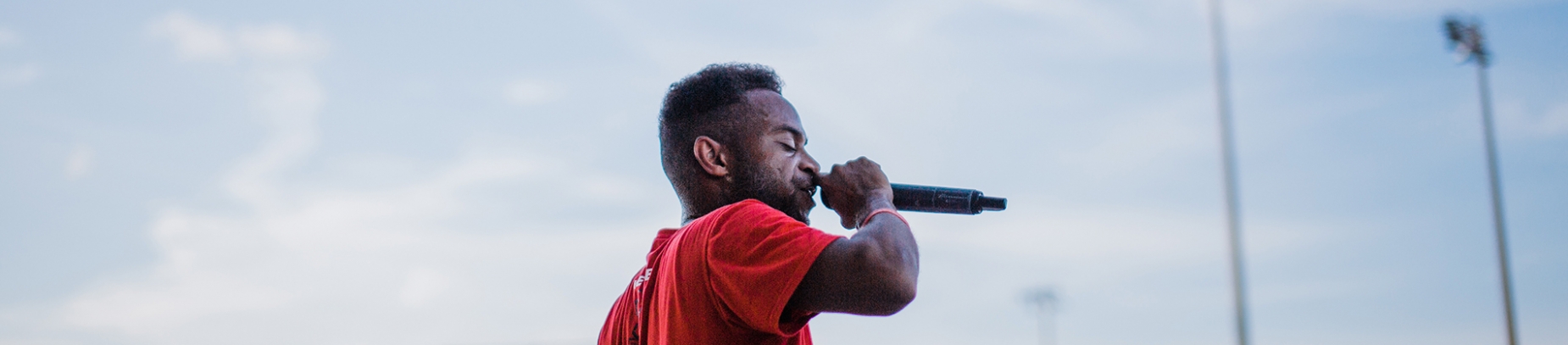 A man in a red top speaking into a microphone A man in a red top speaking into a microphone