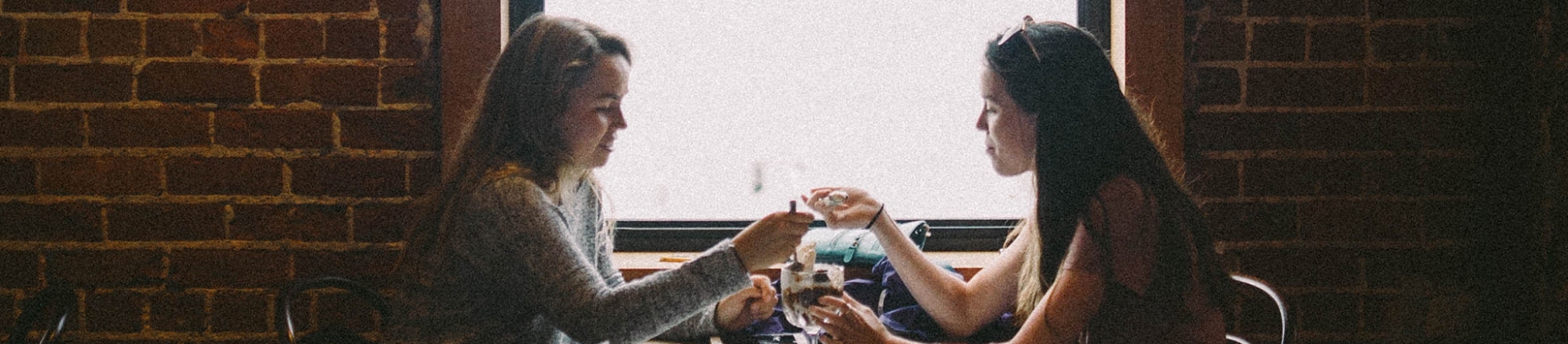 Two friends eating from a ice cream sundae Two friends eating from a ice cream sundae