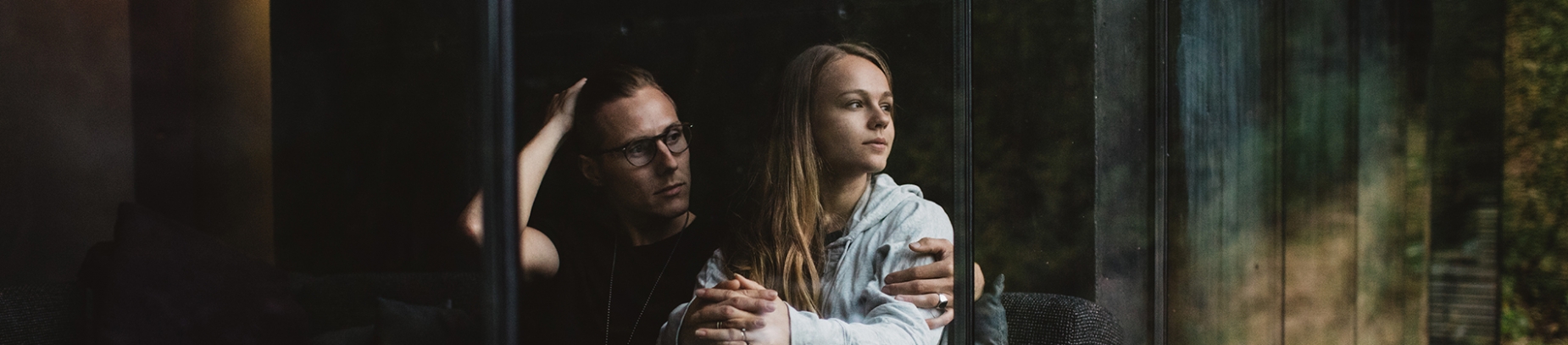A couple sat looking out of a glass window