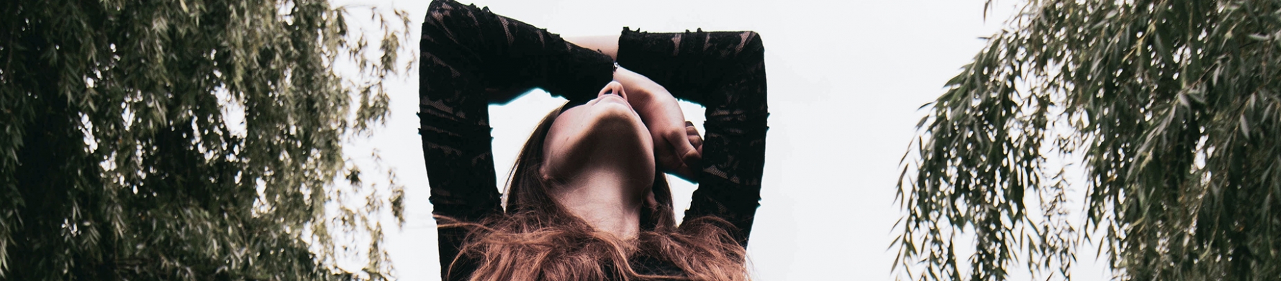 A women looking up to the sky with her arms above her head A women looking up to the sky with her arms above her head
