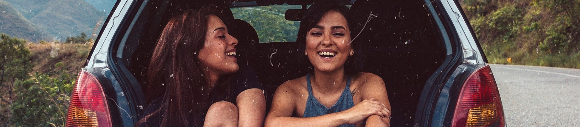 Two friends sat in the back of a car laughing together Two friends sat in the back of a car laughing together