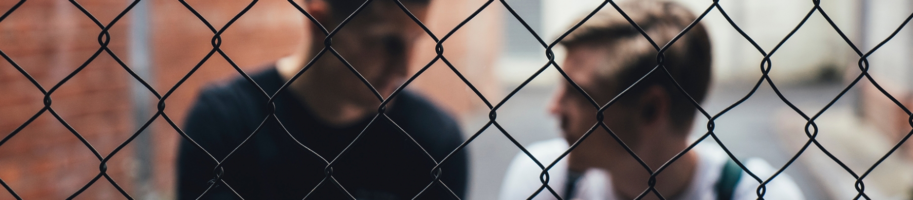Two guys blurred sat behind a metal fence Two guys blurred sat behind a metal fence