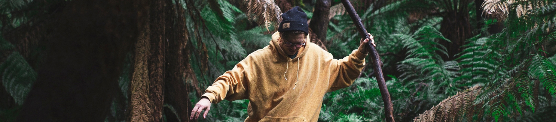 A guy in a yellow hoodie holding a large stick A guy in a yellow hoodie holding a large stick