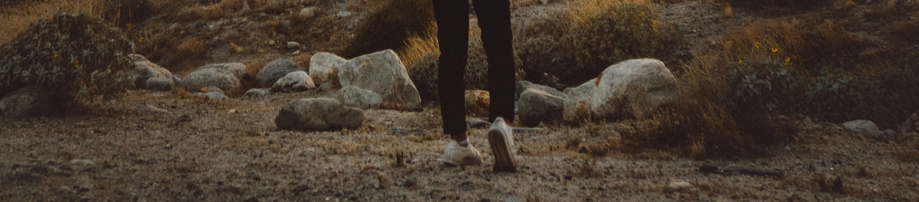 A Man stood by some rocks looking out towards mountains A Man stood by some rocks looking out towards mountains