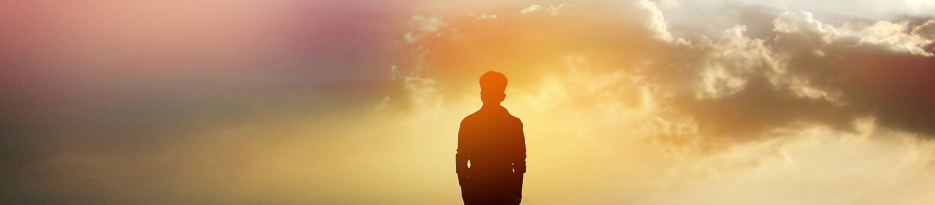 Silhouette of man with coloured sunrise in front of him Silhouette of man with coloured sunrise in front of him