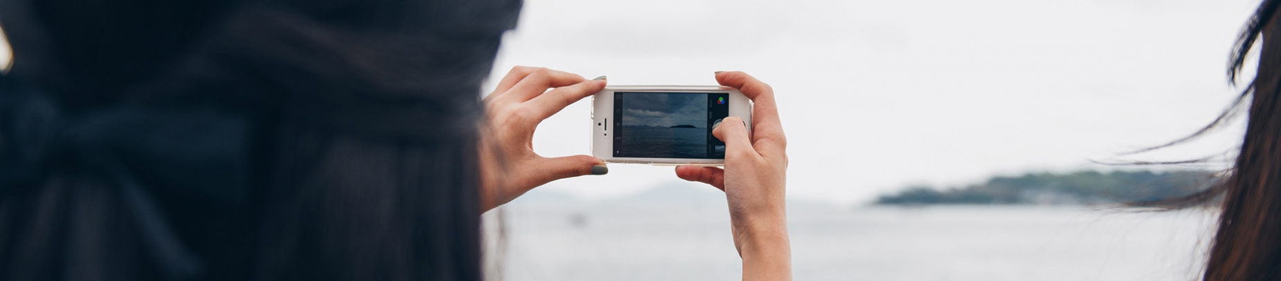 A women taking a photo of the sea and a island A women taking a photo of the sea and a island