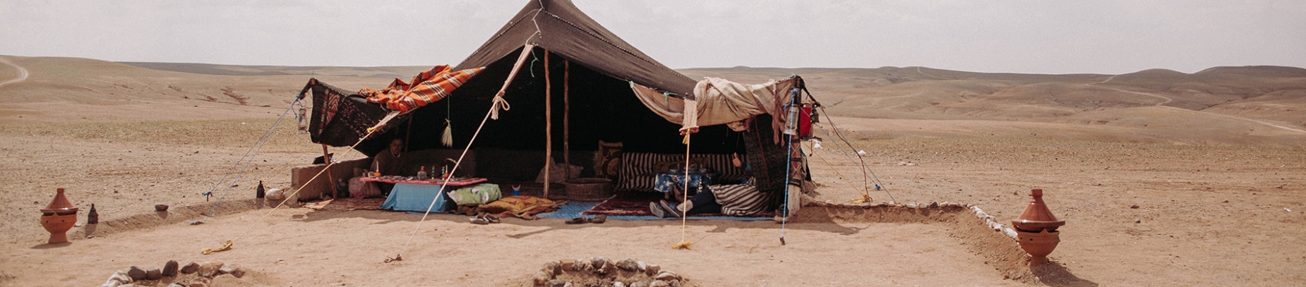 A old tent held up with ropes in the middle of a desert A old tent held up with ropes in the middle of a desert